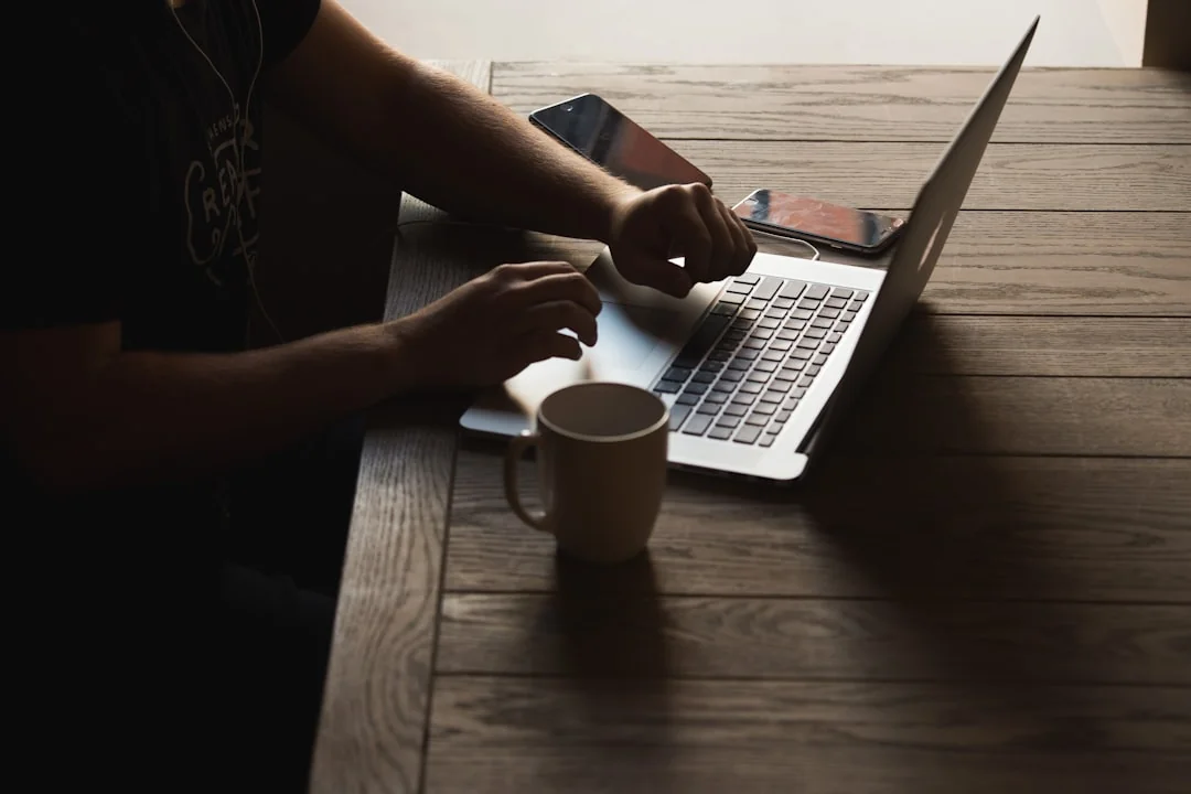 Hands at work on a laptop, with cryptocurrency charts and a smartphone visible, centered on digital finance.